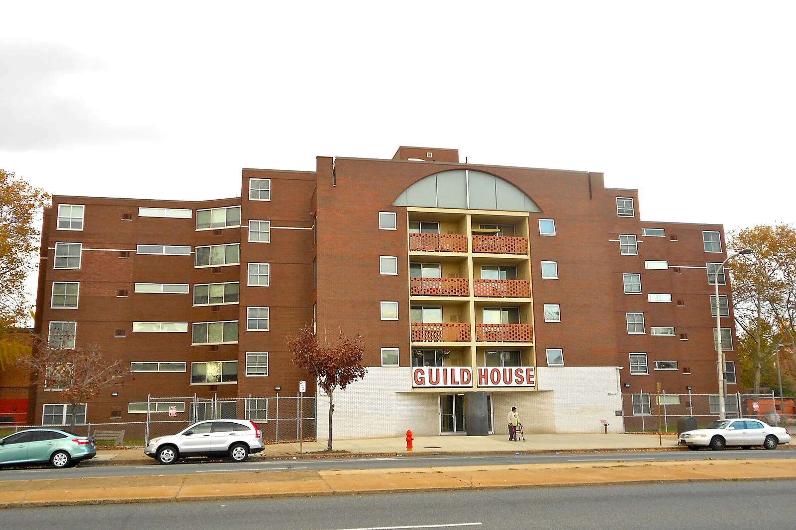 Brick facade of Guild House in Philadelphia with an arched top window and a large name sign above the entrance