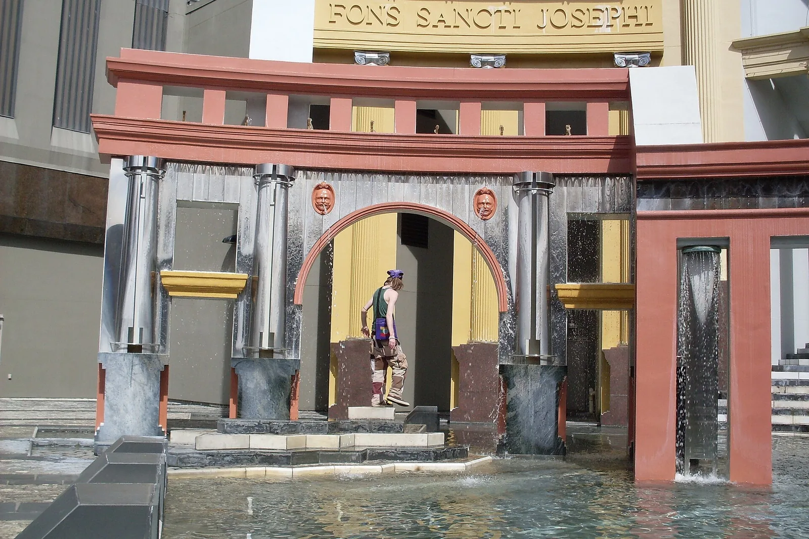 Fountain at Piazza d'Italia in New Orleans with stainless steel columns, a red arch and water running over stone steps