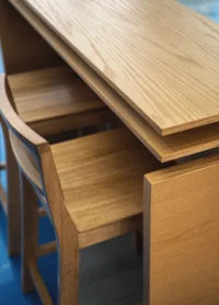 Close view of oak grain on the high table and a stool tucked beneath it