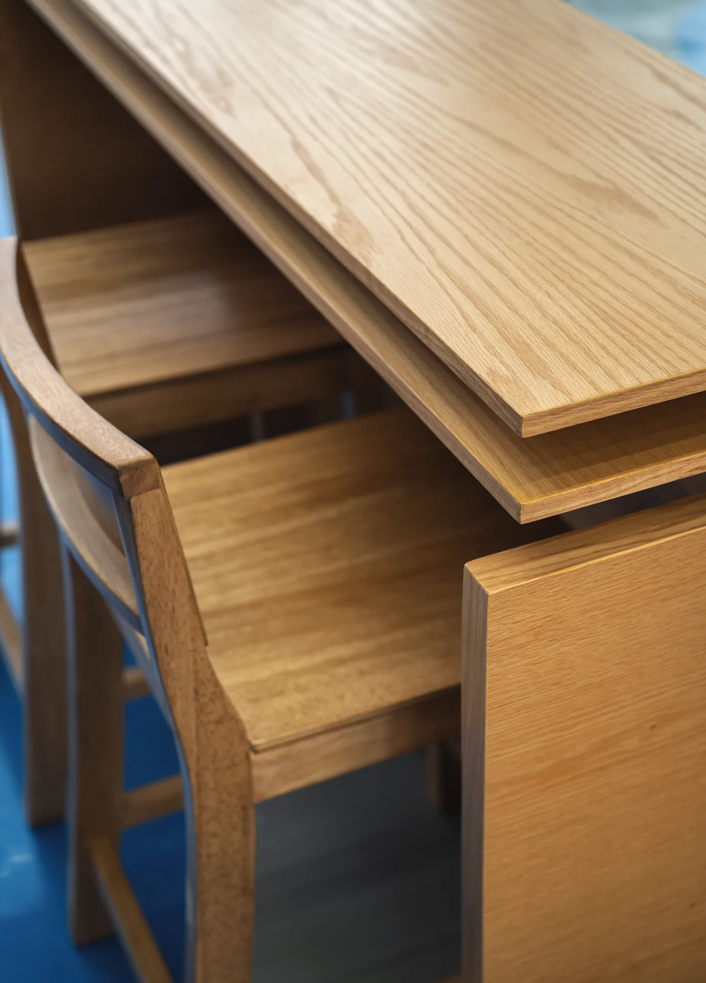 Close view of oak grain on the high table and a stool tucked beneath it