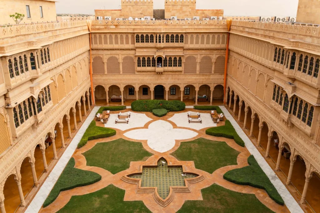 Aerial view of the sandstone courtyard and geometric garden of Suryagarh Palace in Jaisalmer, an example of hotel design rooted in local craft