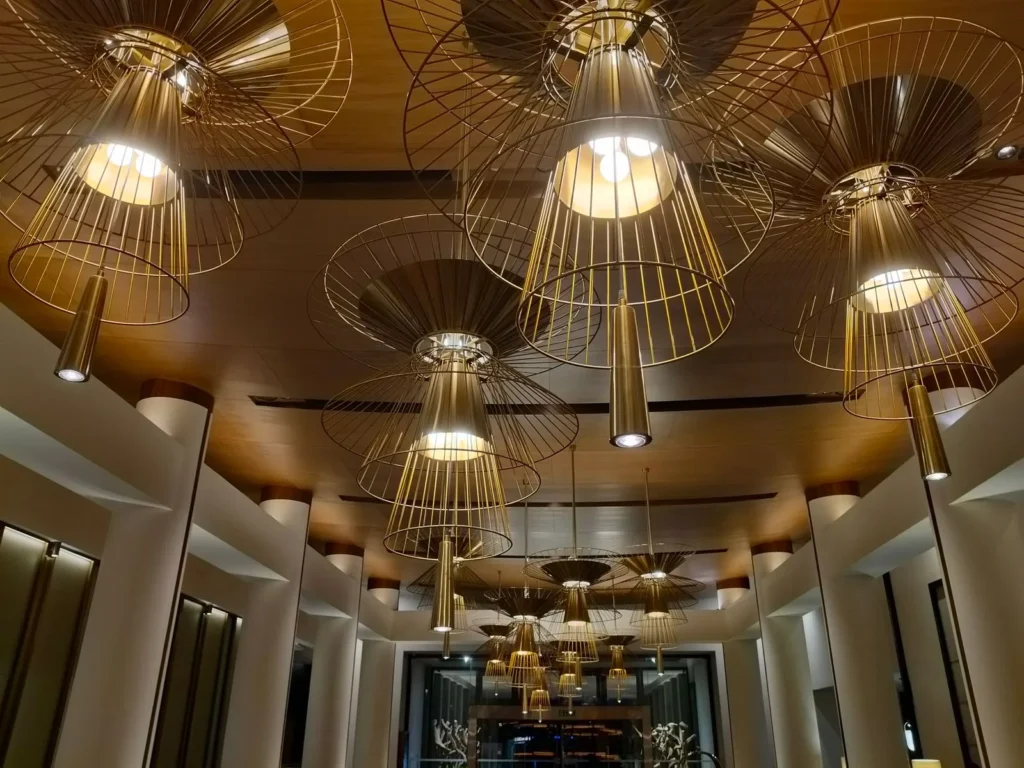 Hotel lobby ceiling hung with oversized gold wireframe pendant lamps