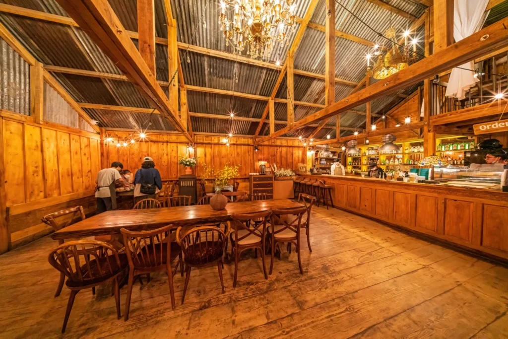 Timber-framed cafe glowing with warm amber pendant light over long wooden tables