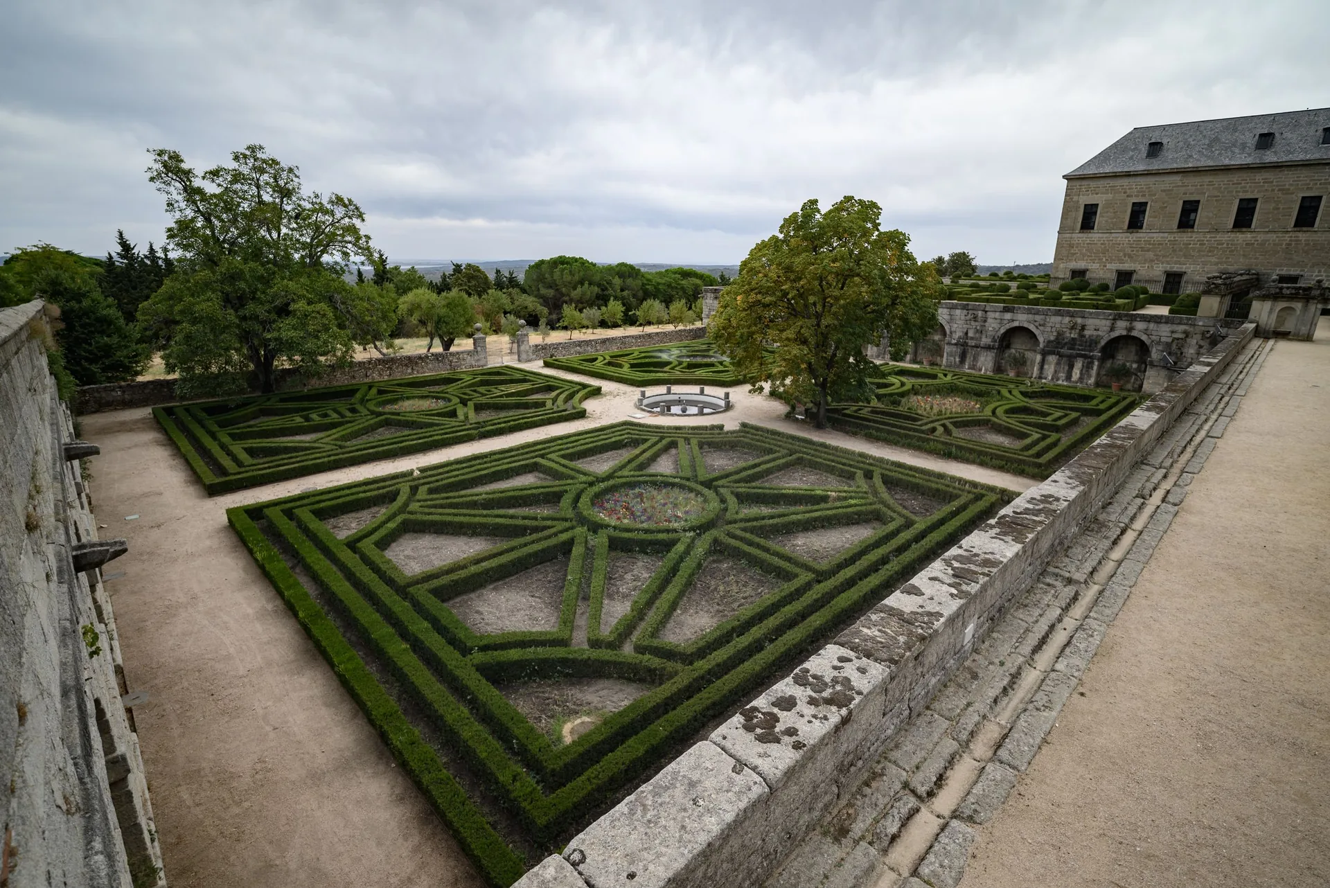 Formal garden style: geometric box hedge parterre with gravel paths beside a stone palace terrace