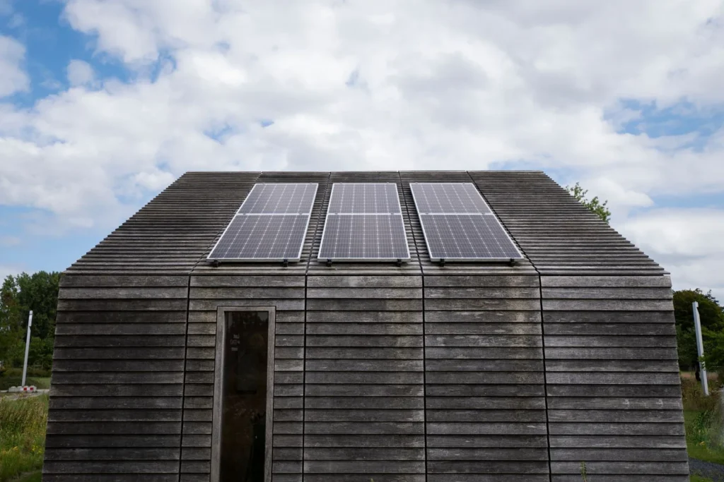Weathered wooden micro house with three solar panels on its pitched roof