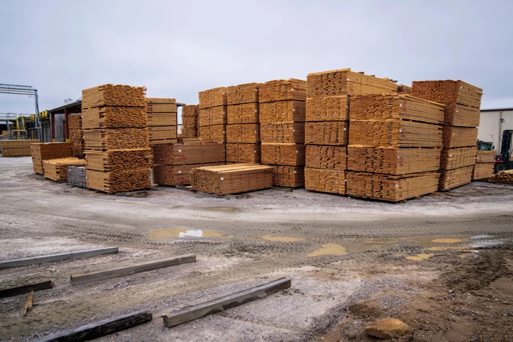 Stacks of sawn timber planks in an outdoor lumber yard, materials assessed in a sustainability analysis in architecture