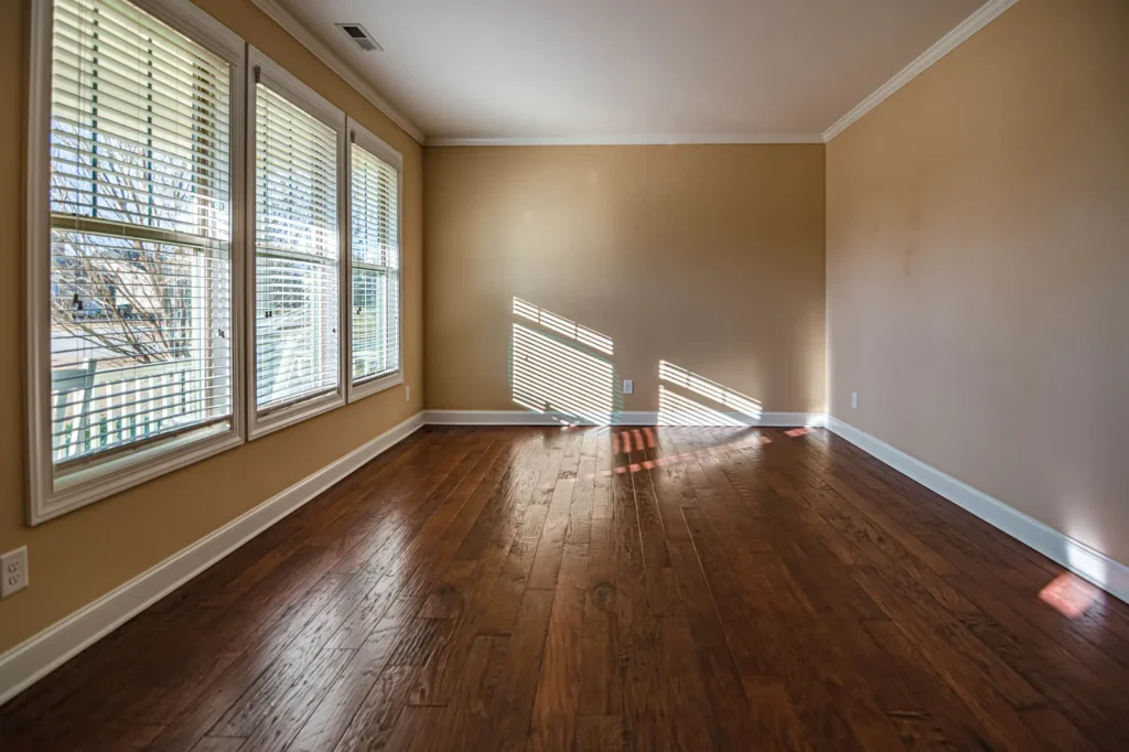 Empty room where sunlight from a row of windows falls in bright patches across a wooden floor