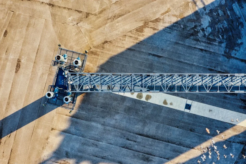 Drone view looking straight down on a crane boom and its shadow across a construction site, one of the innovative construction techniques now used for site surveys