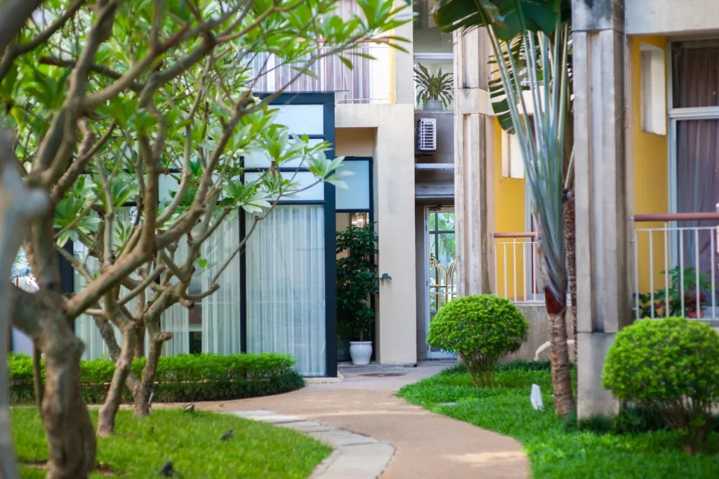 Curving garden path with trees and clipped shrubs between modern apartment buildings