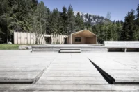 Larch clad snack bar and changing block behind a stepped wooden terrace with a slot in the deck, Lake House Völs by NOA