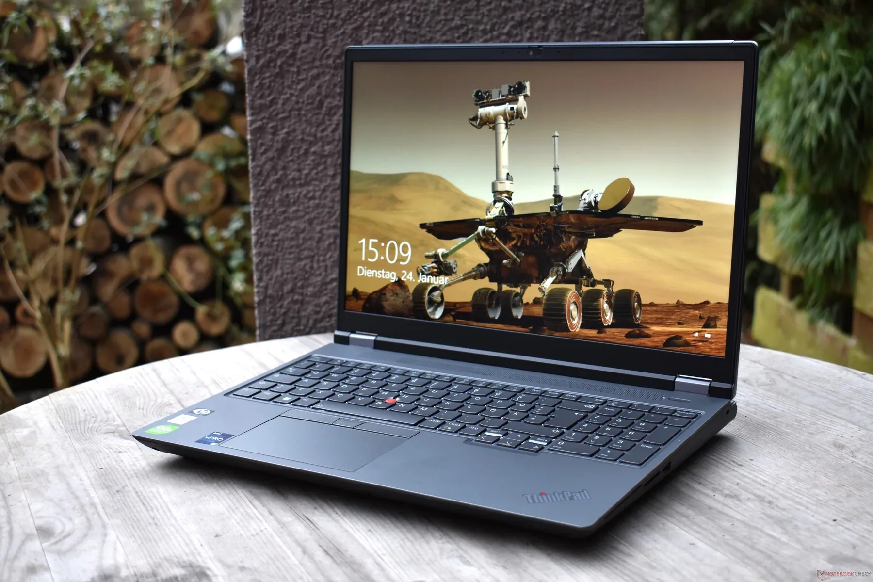 Lenovo ThinkPad P16 Gen 2 workstation open on a round wooden table outdoors, Mars rover wallpaper on screen