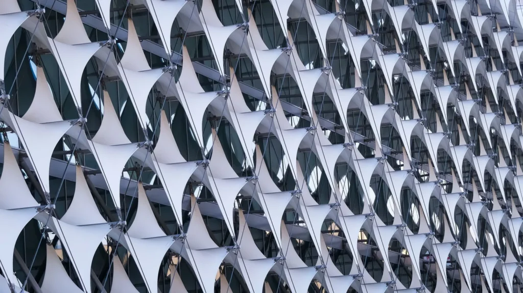 Modern facade design with repeating curved white panels forming a computational screen over glazing