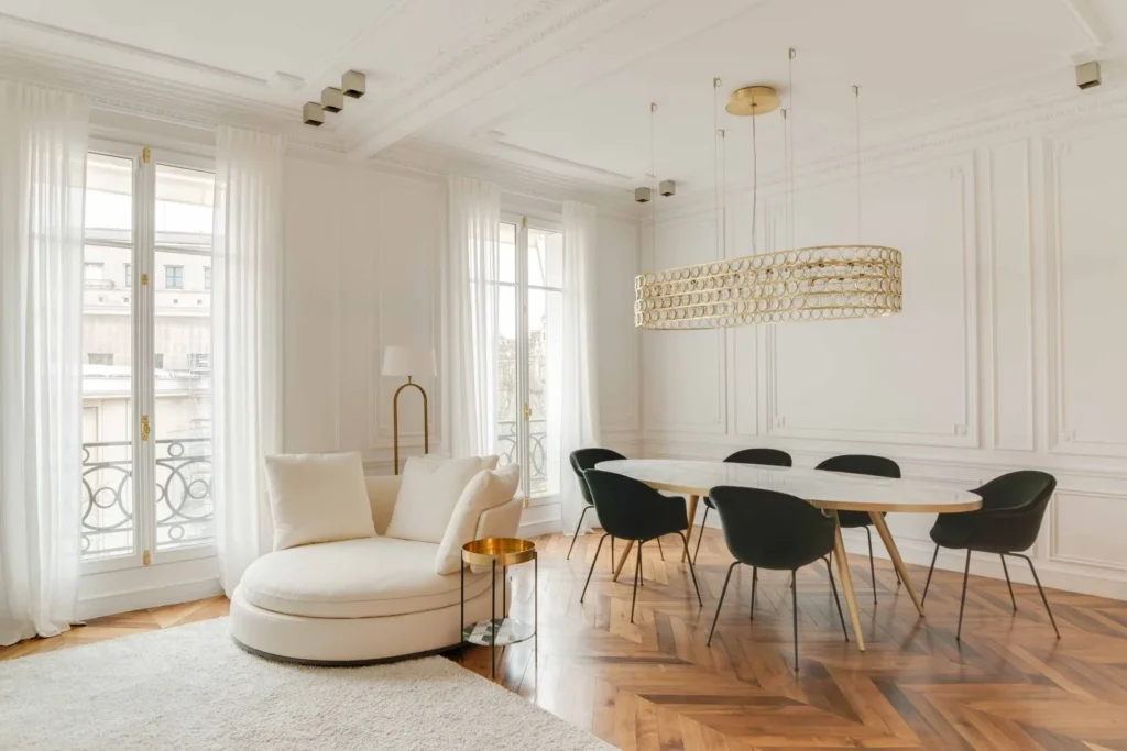 Paneled white room with classic wall moldings, a sculptural modern armchair and a contemporary dining set
