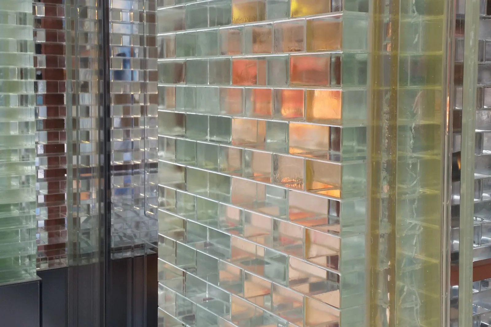 Corner of the Crystal Houses glass brick facade by MVRDV, with the shop interior glowing through the transparent bricks