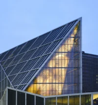 Close view of the sloping glass roof of the Pyramid Hall revealing the illuminated AAhkA artwork inside, New Government Quarter by Nordic Office of Architecture