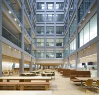 Multi storey atrium of the D-block with a staff canteen of timber tables, benches and leather booths, New Government Quarter by Nordic Office of Architecture