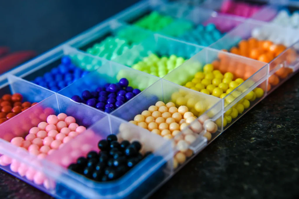 Organizer box of colorful plastic beads sorted by shade, the material behind pixelated street art