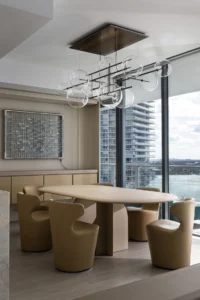 Dining room with a sand toned oval stone table, camel chairs and a chandelier of glass globes on a bronze frame, PS Apartment by Nar Design Studio