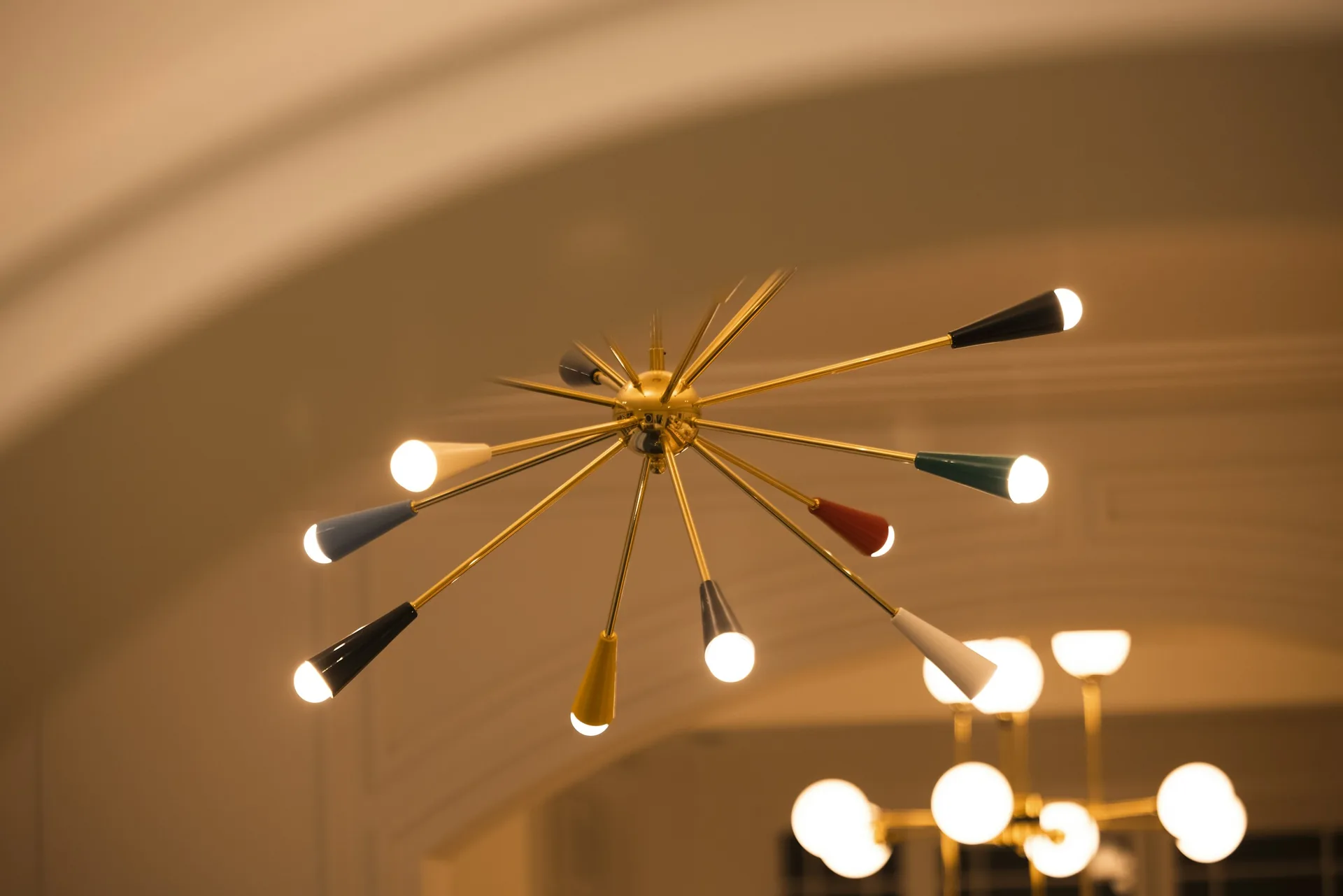 Sputnik style chandelier with brass arms and coloured cone shades radiating from a central ball