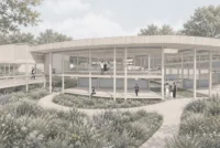 Glazed circular pavilion with a deck and timber columns facing a curved path through tall grasses and flowering plants, Sattva: The Healing Village by Anindita Shrivastava