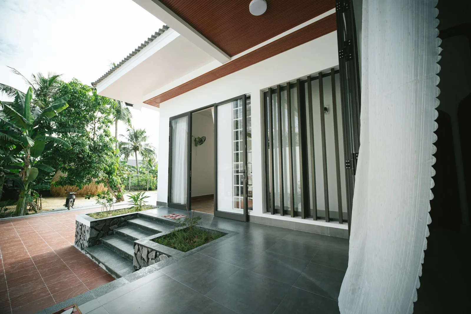 Contemporary house opening onto a planted patio, showing the threshold between interior and garden