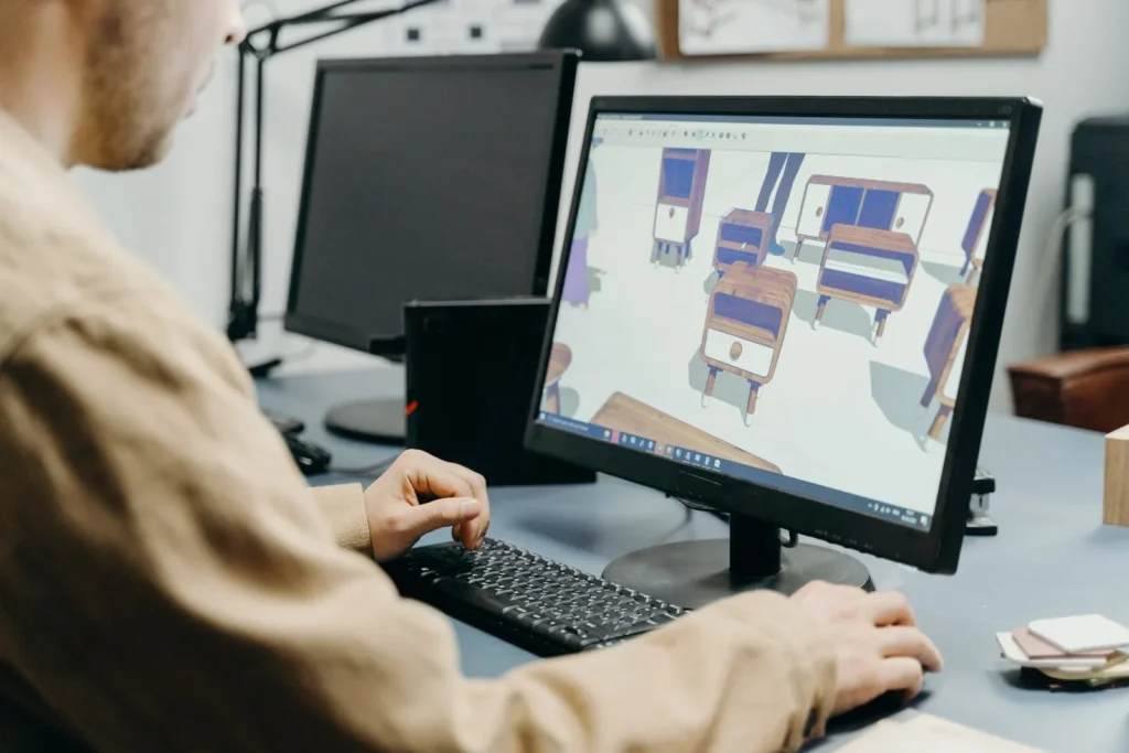 Designer modelling 3D furniture pieces on a large monitor at an office desk