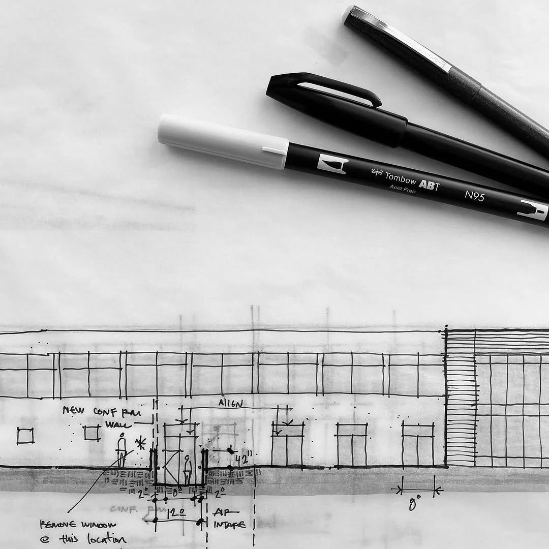 Pencil elevation sketch of a street facade in progress with dimension notes and markers resting on the paper