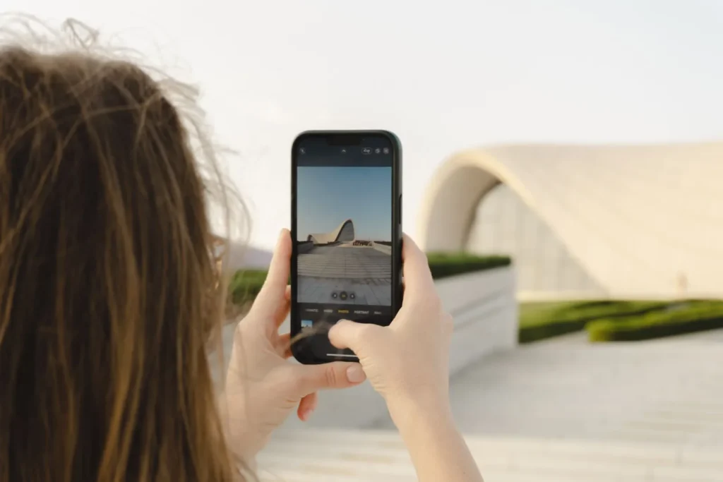 Visitor framing the curving white Heydar Aliyev Center in Baku on a smartphone, everyday content behind social media for architects