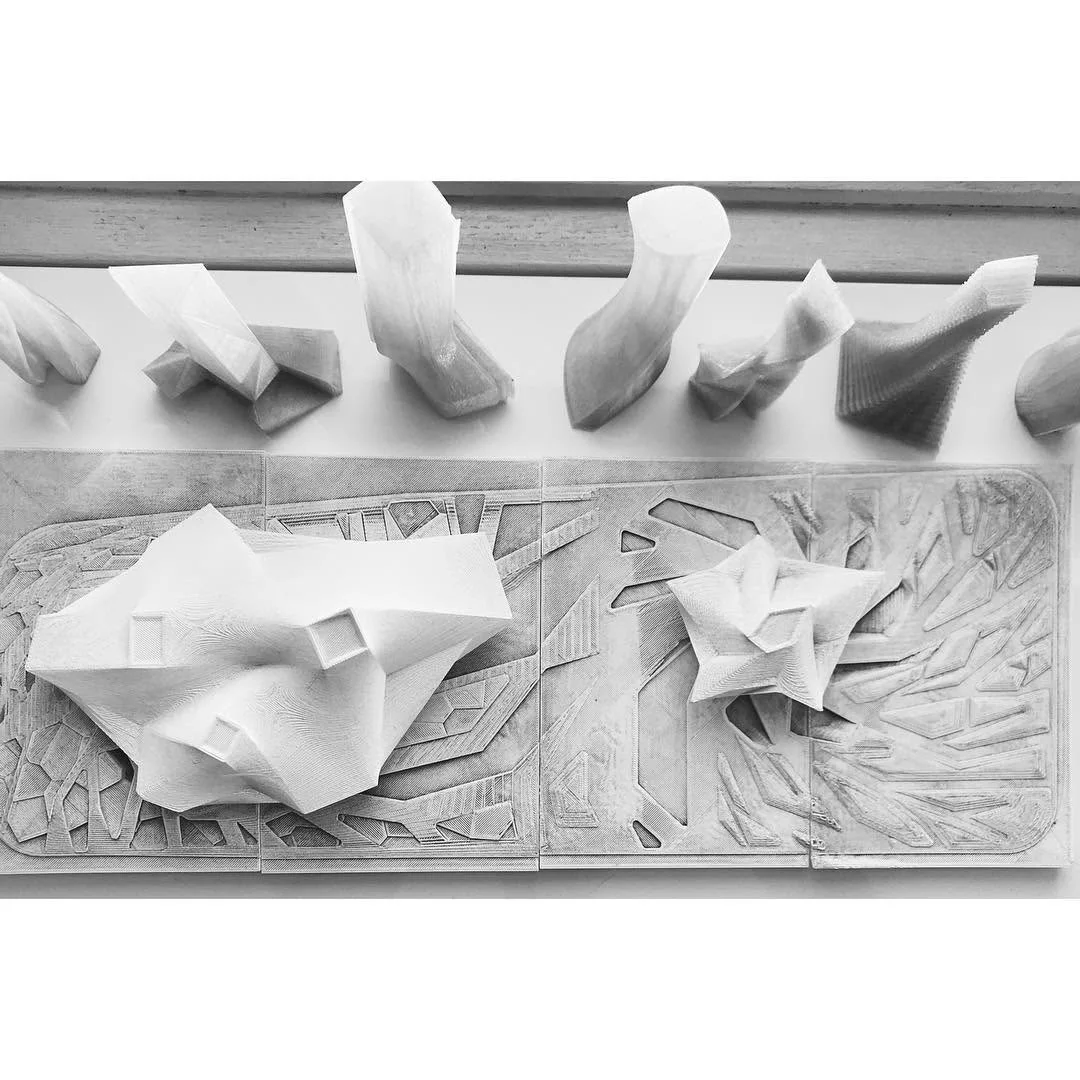 Crumpled plaster study models lined up on a shelf above a site base, exploring free form shapes