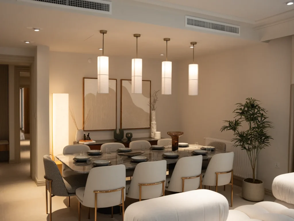 Dining room with a row of cylindrical paper pendant lights above a marble table and upholstered chairs