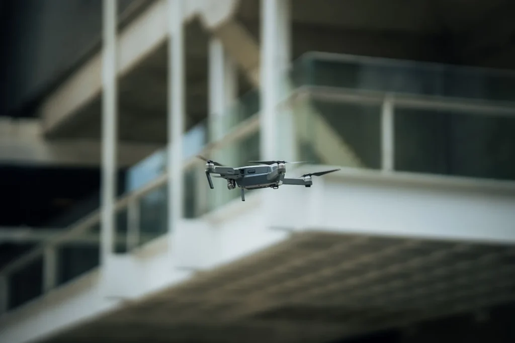 Small quadcopter drone hovering beside the balconies of a concrete building