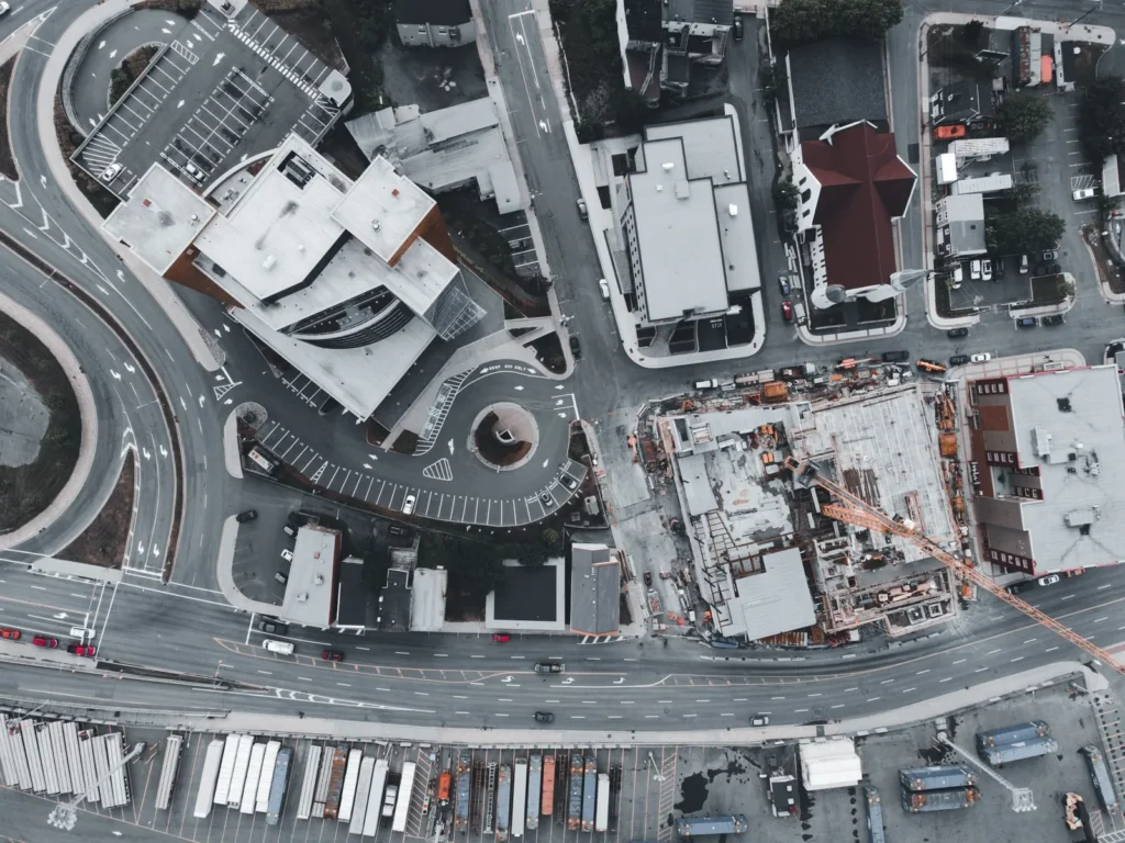 Top-down aerial view of a city block with a construction site, roads and parked trucks