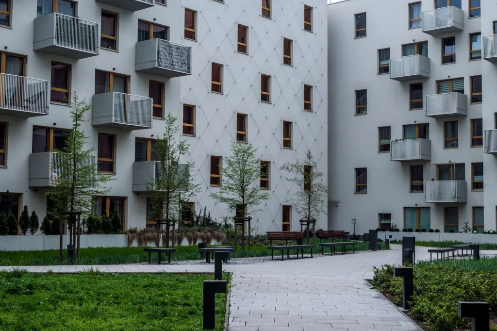 Landscaped courtyard with benches and paths between white apartment blocks with balconies