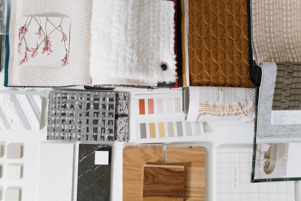 Fabric, carpet, stone and wood samples laid out with paint colour cards on a white table