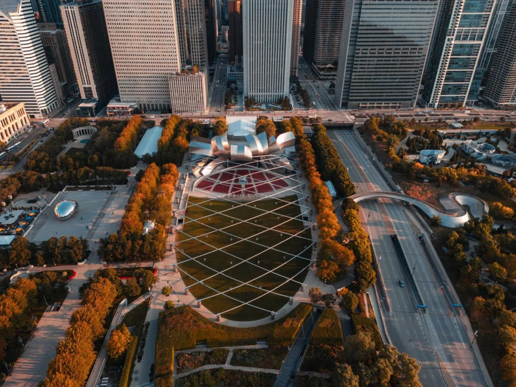 Aerial view of Millennium Park in Chicago with the Pritzker Pavilion lawn and its steel trellis framed by autumn trees