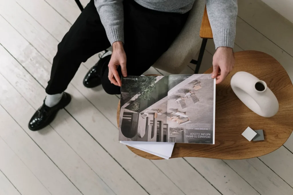 Person seated at a small table holding an open architecture magazine