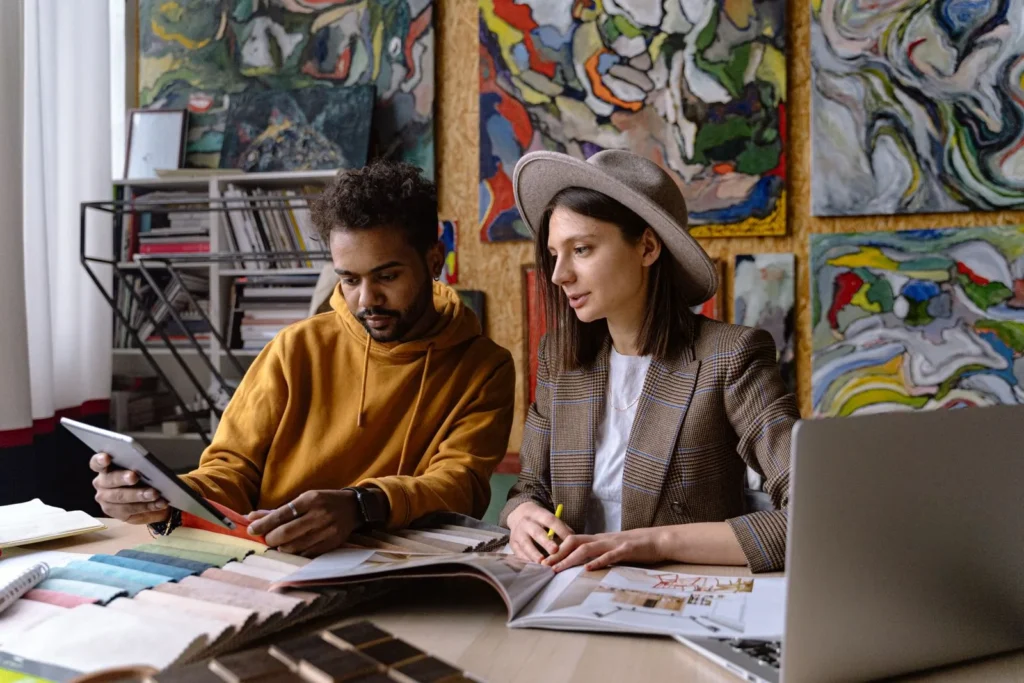 Two designers reviewing fabric swatches and a tablet together at a studio table