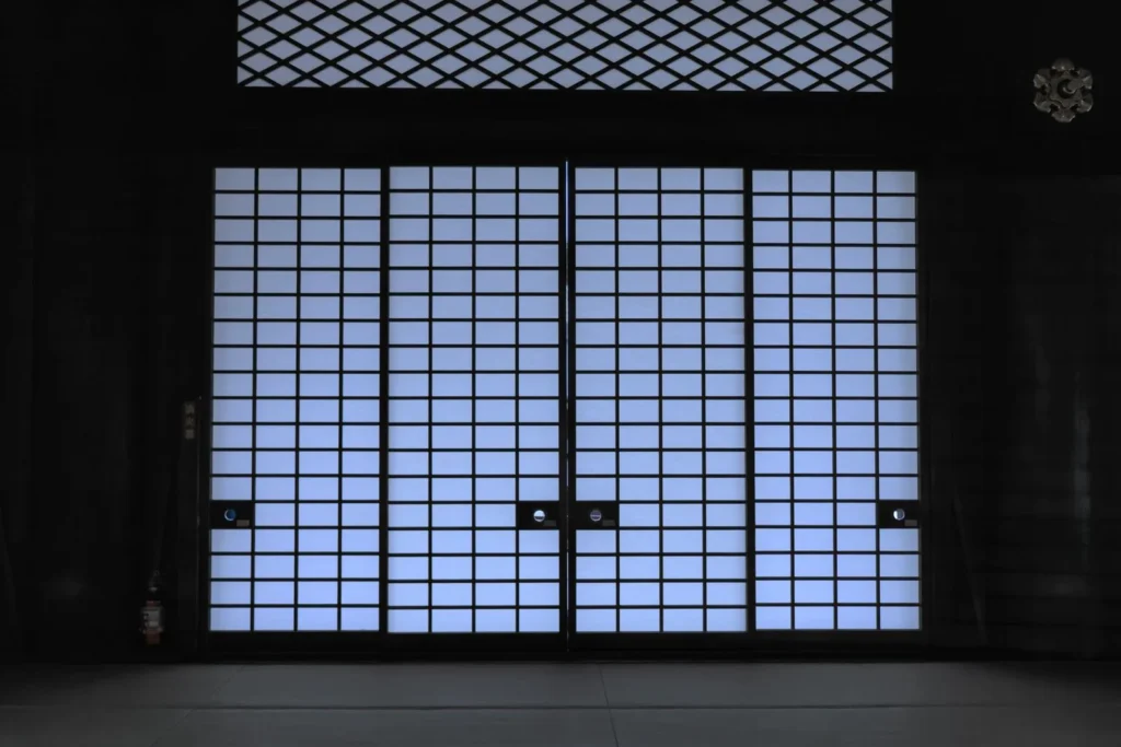 Wall of paper shoji screens glowing with soft daylight inside a dim traditional Japanese room