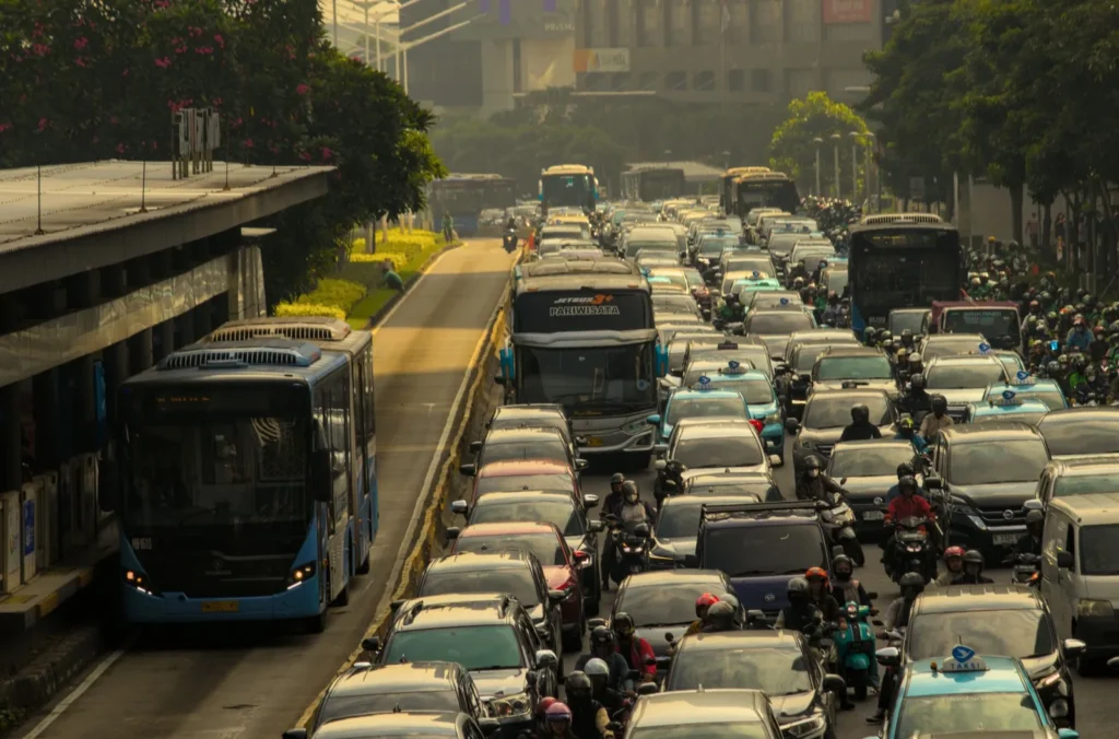 Buses in a dedicated lane beside a road packed with cars and motorbikes, a common urban mobility bottleneck
