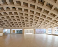 Coffered LVL gridshell ceiling spanning the open hall above a pale timber floor, Wisdome Stockholm by Elding Oscarson