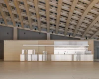 Stainless steel café counter under the deep lattice of the timber roof, Wisdome Stockholm by Elding Oscarson