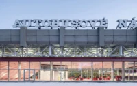 Glazed waiting hall with a red interior below the concrete roof fascia and the original lettering, Zvonařka Bus Station by CH+K